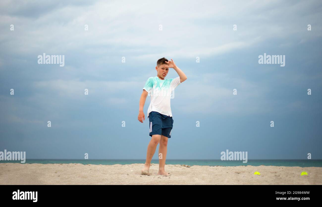 Il ragazzo si allena sulla sabbia vicino al mare. Preparazione fisica generale. Giocatore di tennis. Foto Stock
