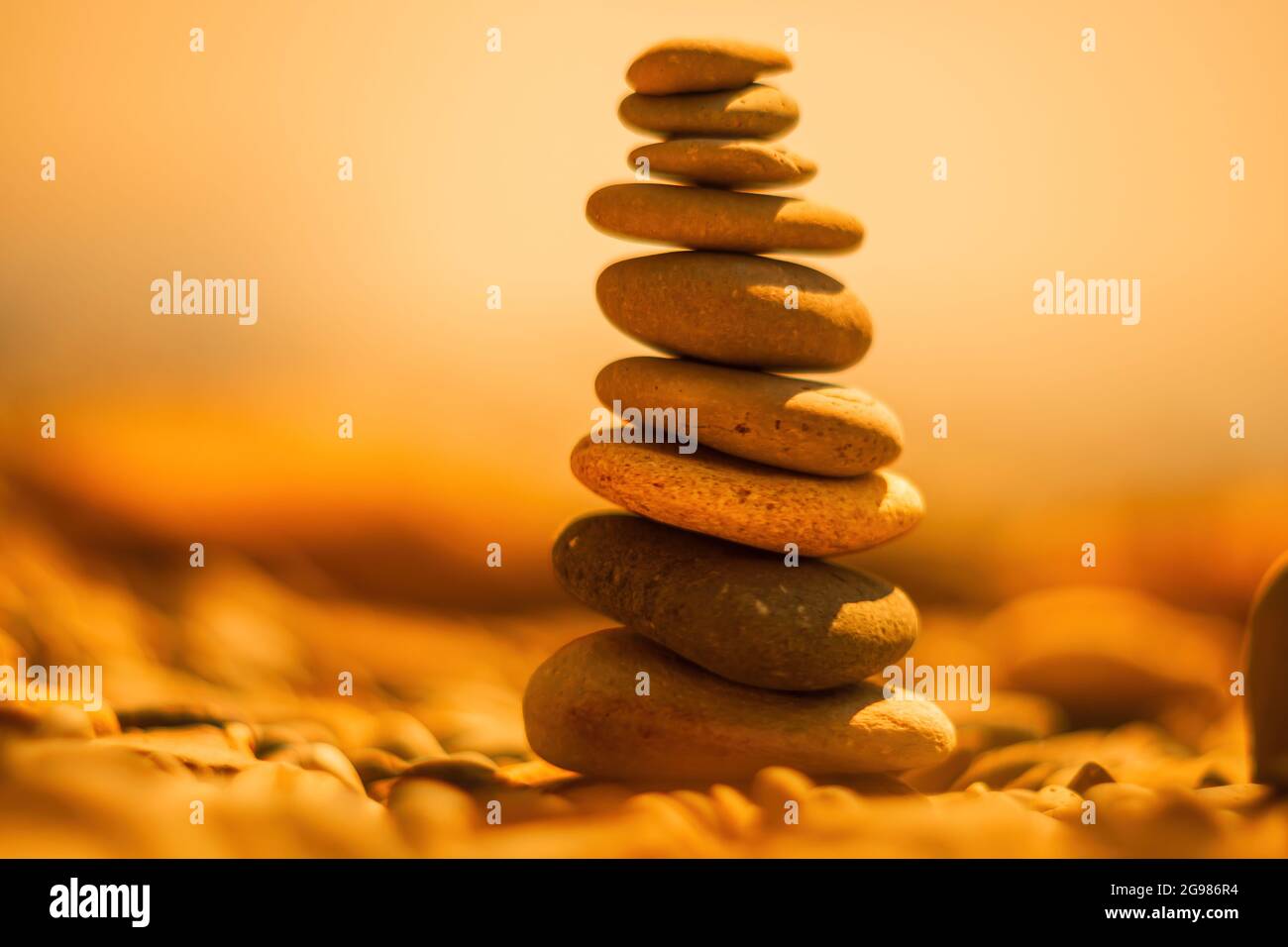 Equilibrata piramide di ciottoli sulla spiaggia in una giornata di sole. Abstract Sea bokeh sullo sfondo. Messa a fuoco selettiva. Pietre Zen sulla spiaggia di mare, meditazione Foto Stock