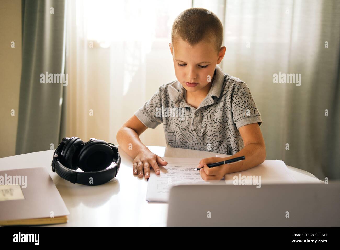 Scolaresche che scrivono in un notebook e usano un computer portatile mentre si lavora a casa o durante una lezione online. Concetto di formazione online. Foto Stock