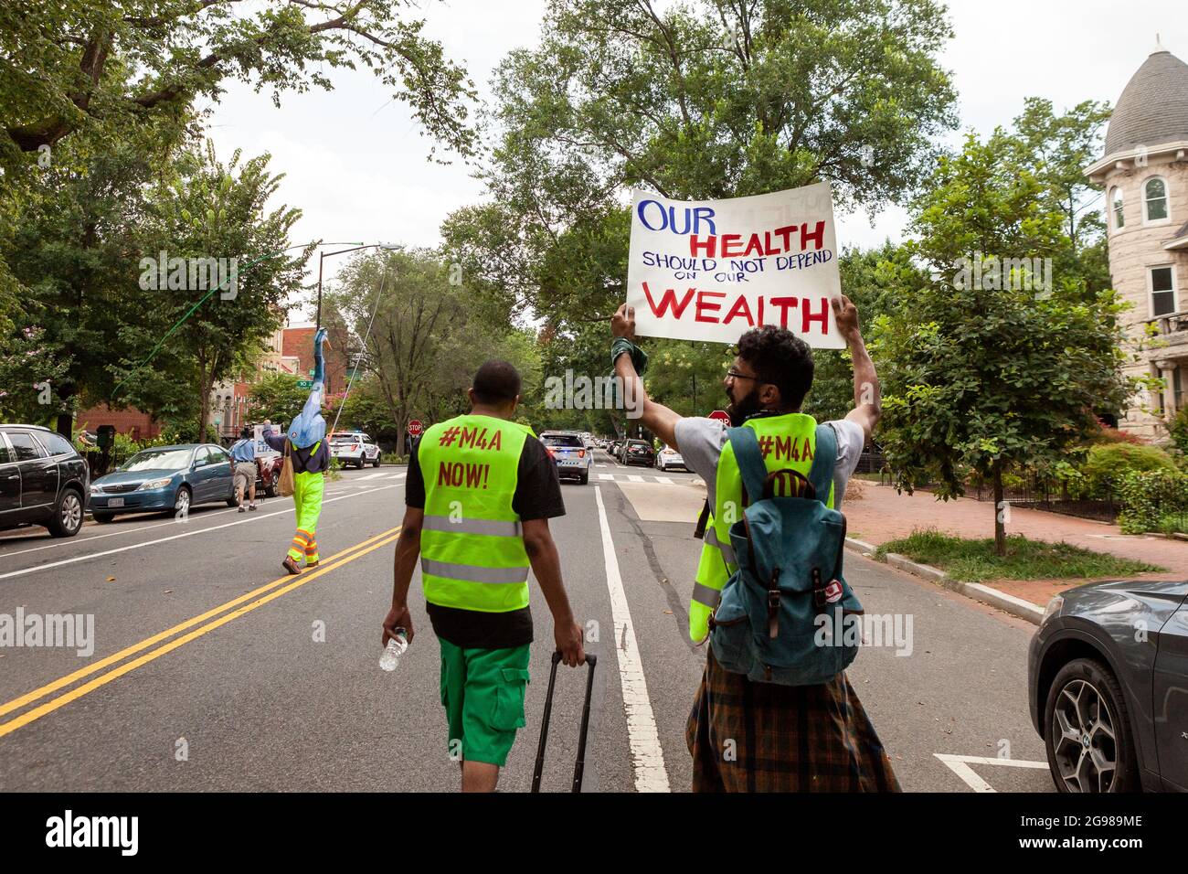 Washington, DC, USA, 24 luglio 2021. Nella foto: I volontari in giubbotti gialli guidano la marcia DC per Medicare per tutti. la marcia fa parte di una domanda nazionale di assistenza sanitaria universale, con eventi in 56 città. Credit: Alison Bailey / Alamy Live News Foto Stock