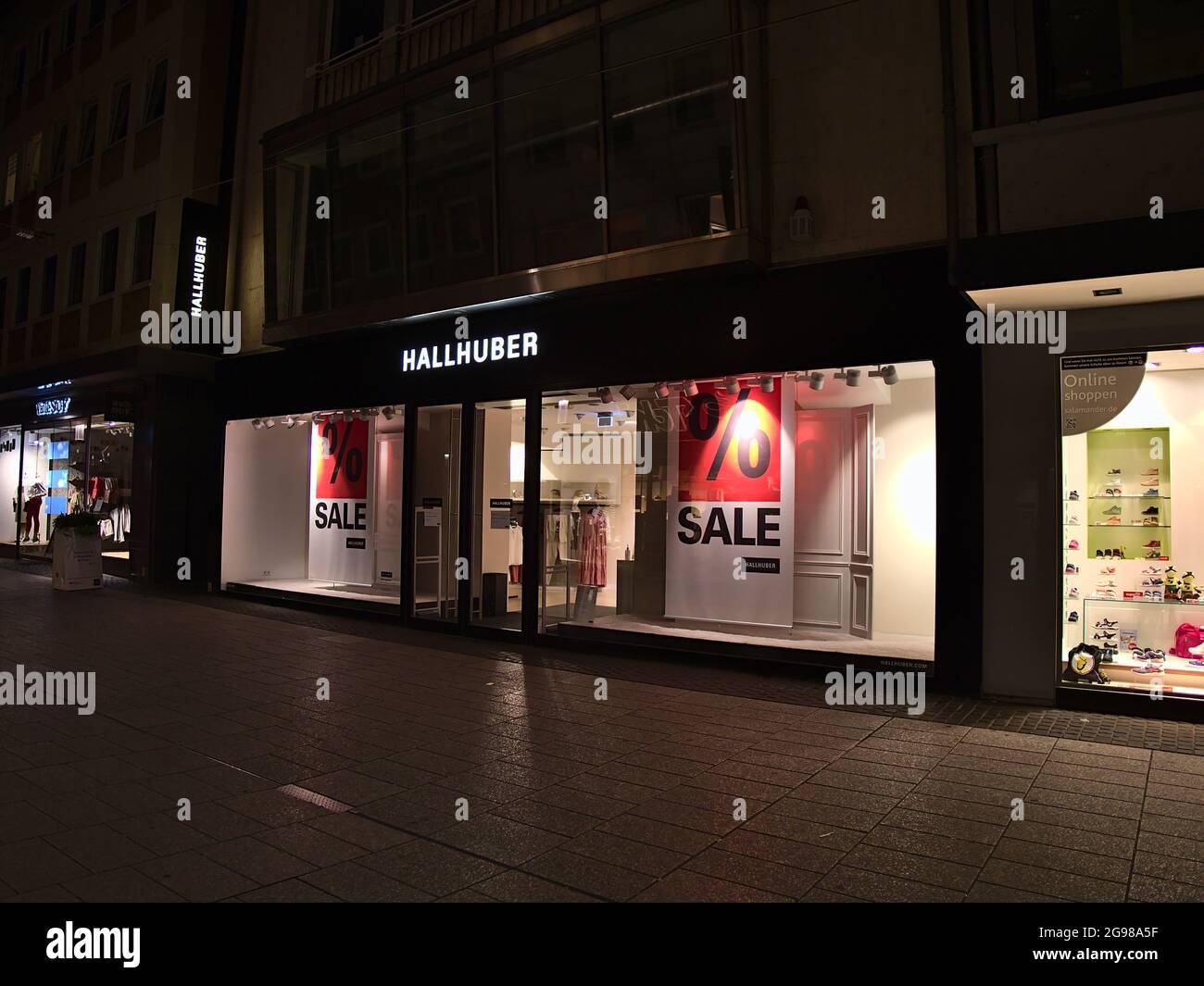 Vista del negozio illuminato della catena di abbigliamento di moda Hallhuber  GmbH con logo aziendale sopra l'entrata in una via vuota dello shopping nel  centro di Coblenza Foto stock - Alamy