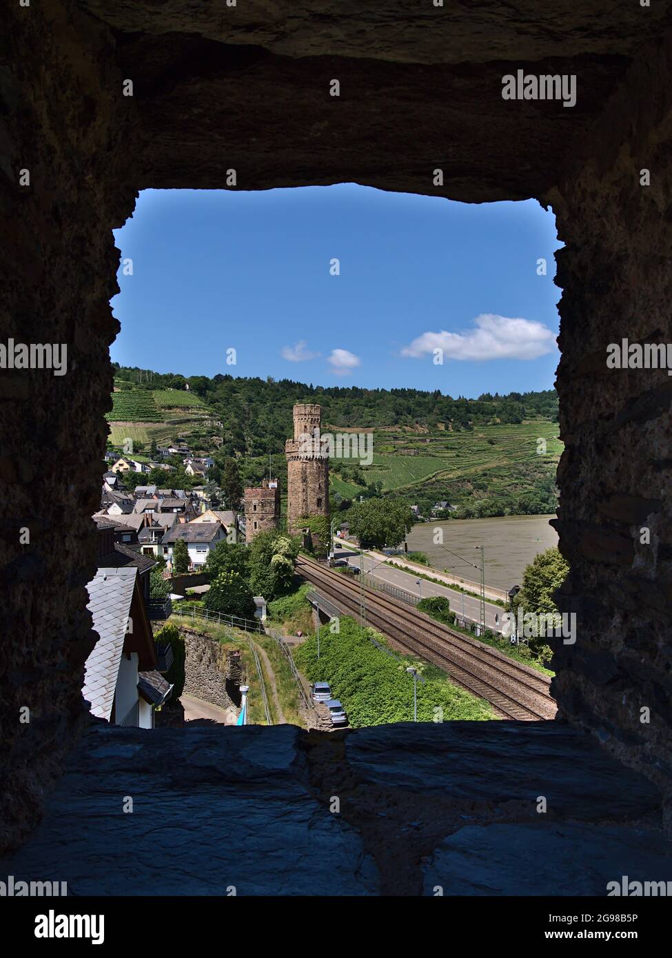 Splendida vista sulle mura storiche della città e sulla torre di guardia attraverso una finestra in pietra nel villaggio di Oberwesel, situato sulla riva del fiume Reno, con binari ferroviari. Foto Stock Splendida vista sulle mura storiche della città e sulla torre di guardia attraverso una finestra in pietra nel villaggio di Oberwesel, situato sulla riva del fiume Reno, con binari ferroviari. Foto Stock