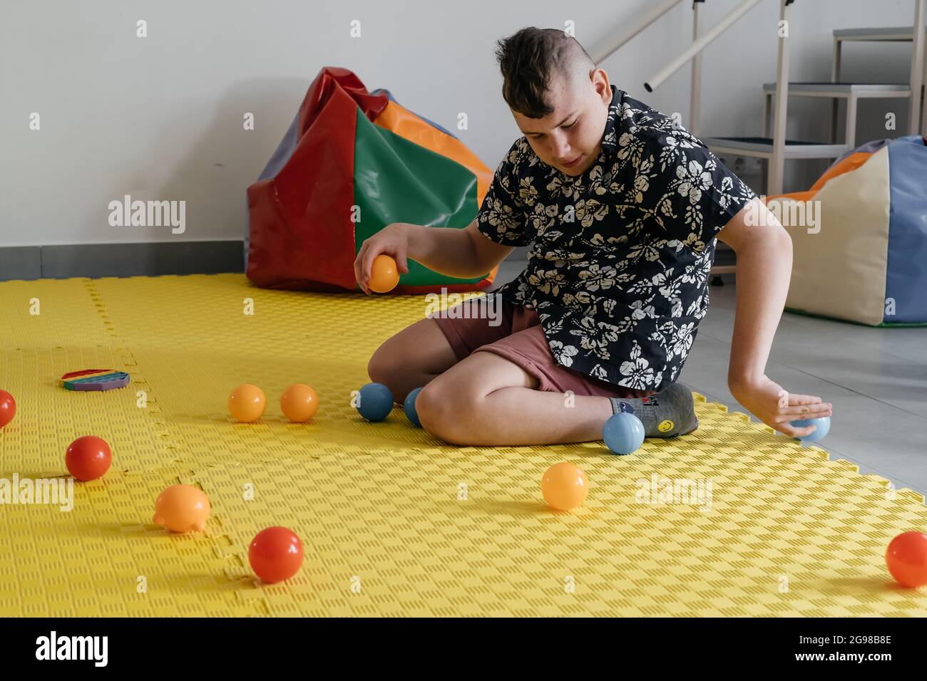 I bambini con disabilità che ottengono l'attività sensoriale con i giocattoli, le palle, i piccoli oggetti, il ragazzo della paralisi cerebrale che gioca il gioco calmante, addestrando le abilità fini del motore Foto Stock