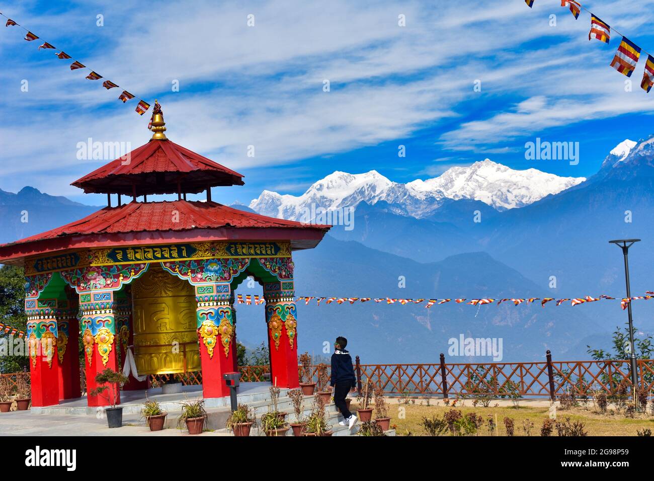 Una grande ruota di preghiera buddista con uno splendido paesaggio montano sullo sfondo del Monte Kanchenjunga Foto Stock