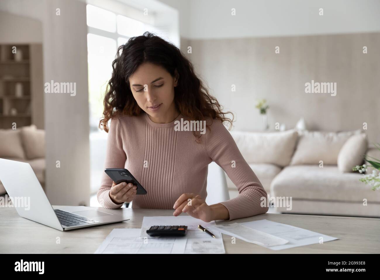 Donna latino paga le fatture sulle cellule calcolano sulla macchina Foto Stock