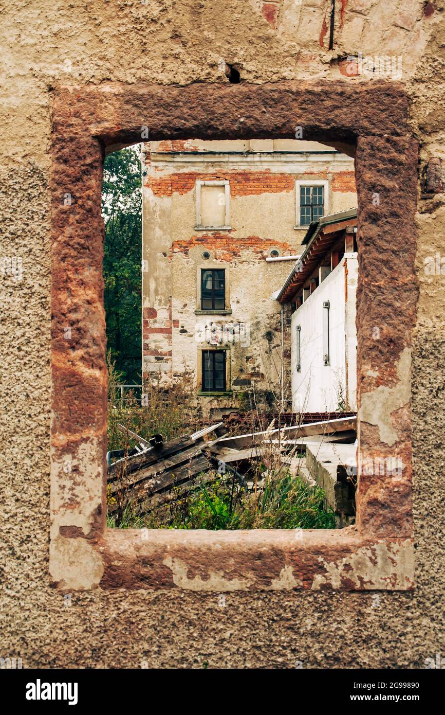 vecchio abbandonato e correre giù edificio della fabbrica fotografato attraverso un telaio della finestra di arenaria senza finestra Foto Stock