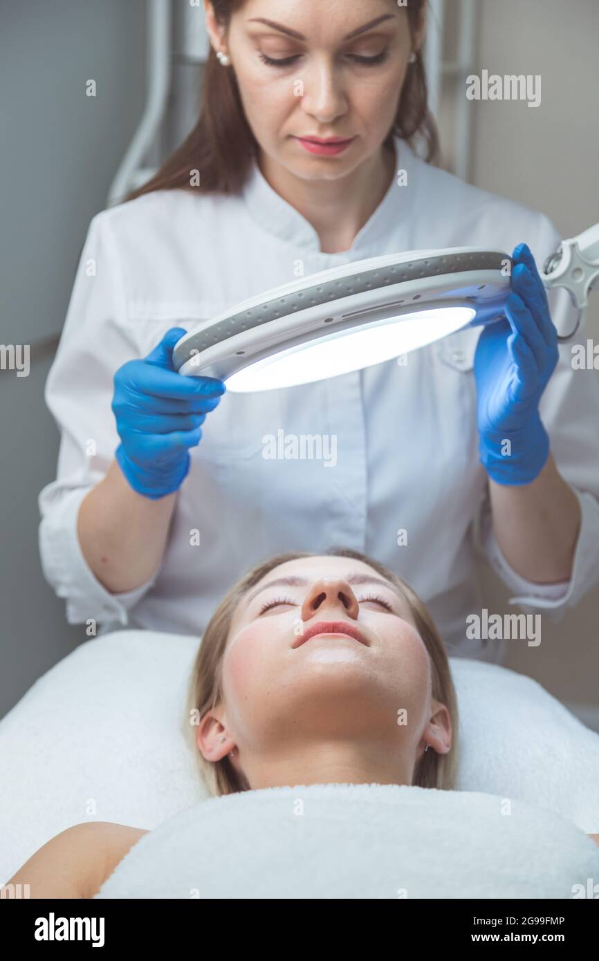 Il medico estetista sta esaminando il viso della donna con una lampada  speciale Foto stock - Alamy