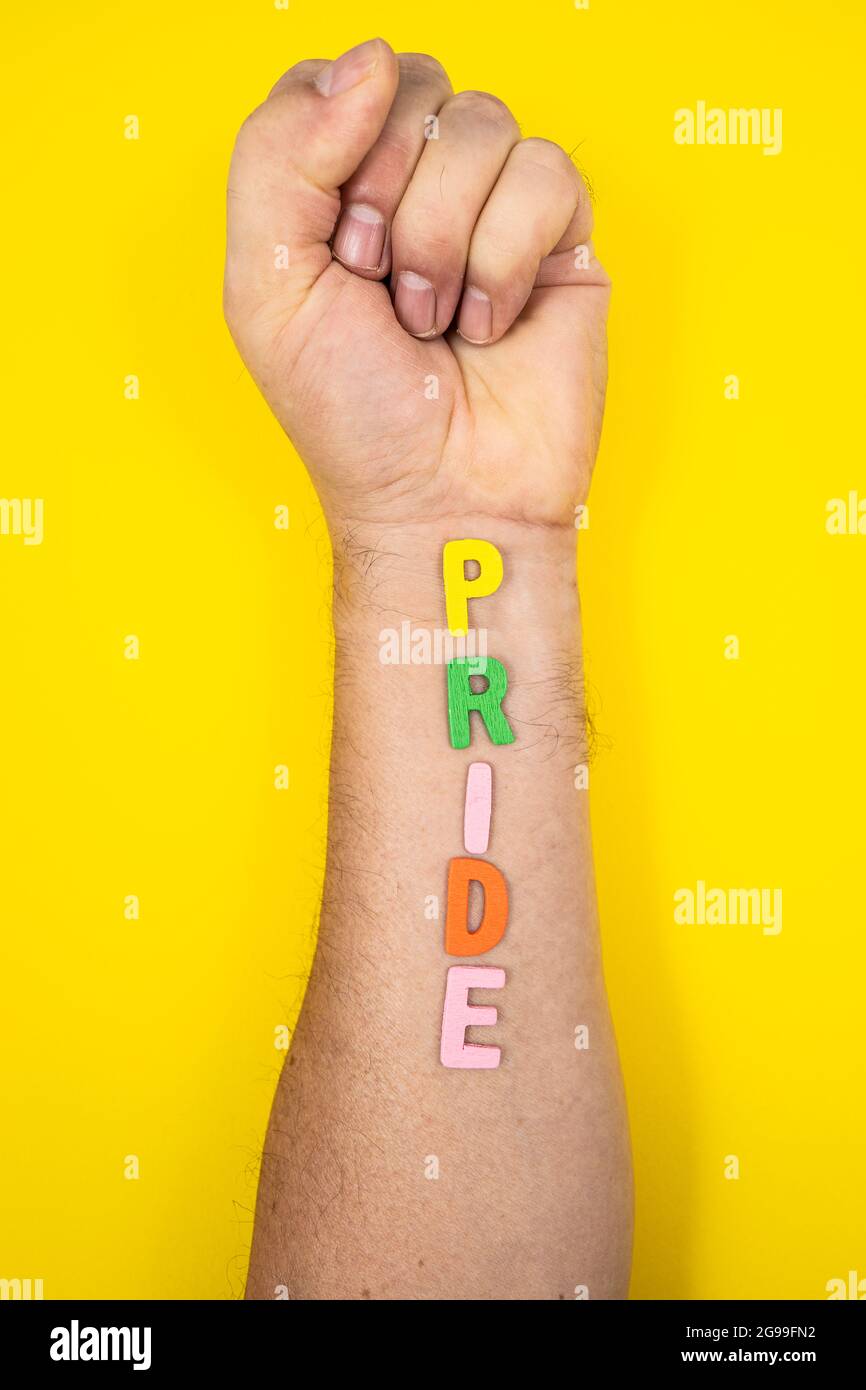 Un braccio con un pugno chiuso con l'iscrizione multicolore Pride Foto Stock