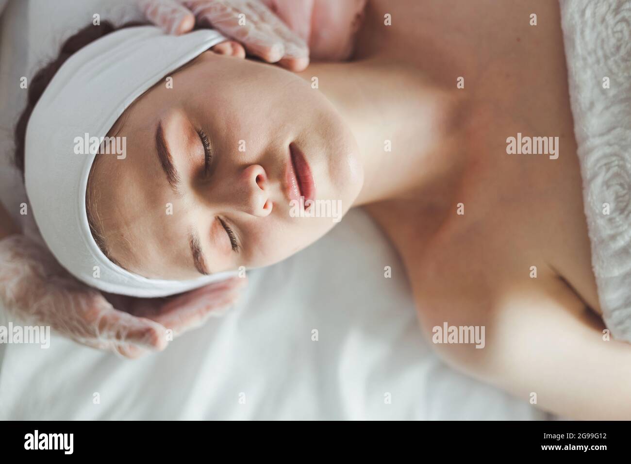 Medico che esamina la faccia della giovane donna prima delle procedure cosmetiche Foto Stock