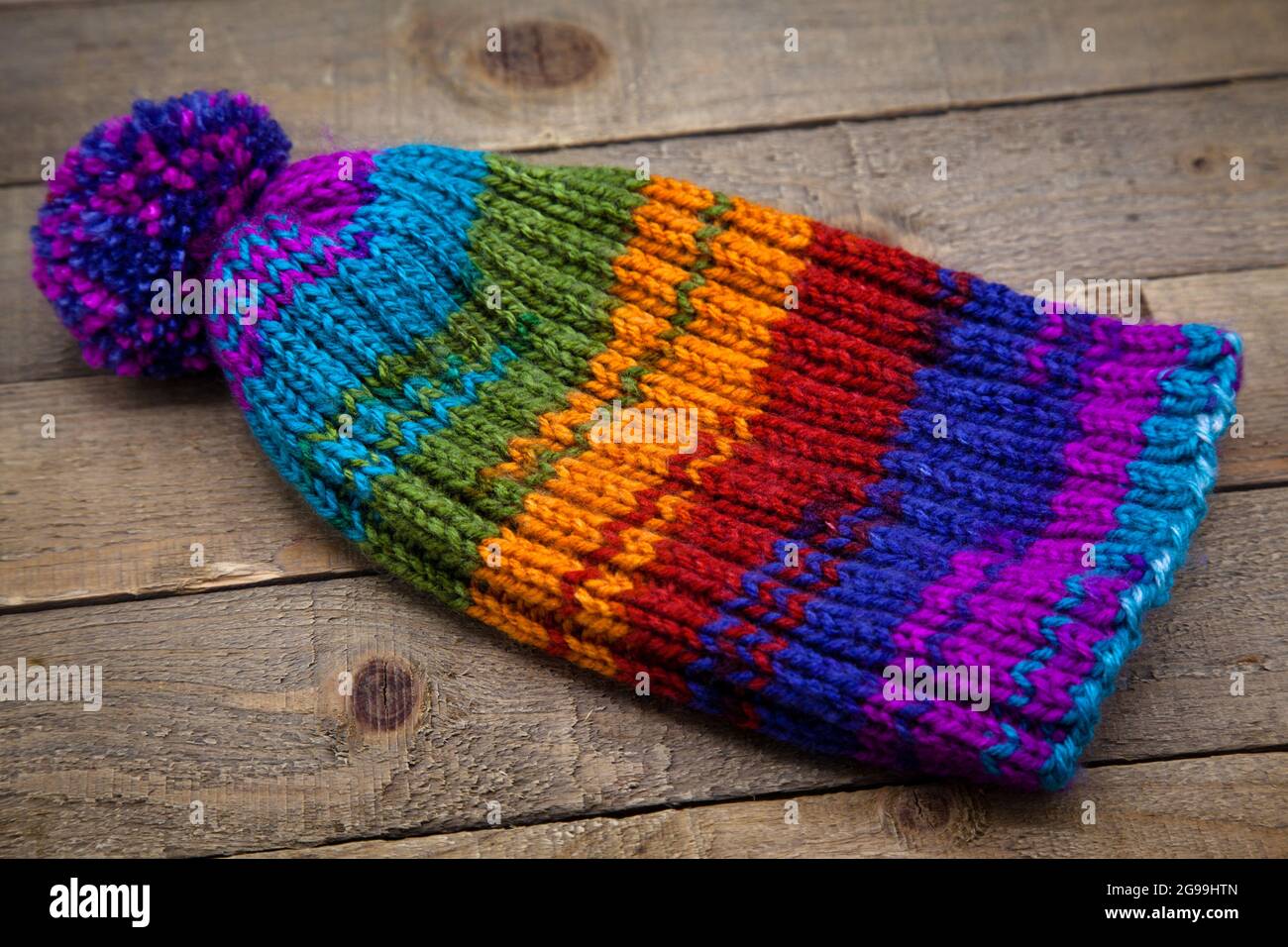 Lana lavorata a mano maglia inverno cappello molto colorato isolato su  sfondo di legno Foto stock - Alamy