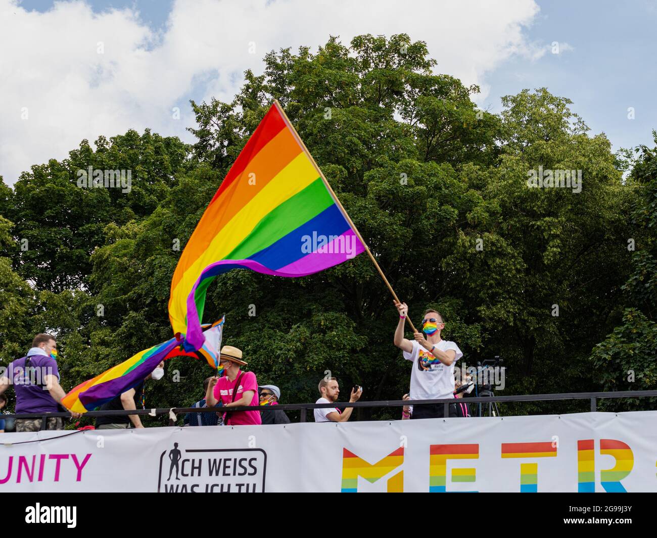 Berlino, Germania - 24 luglio 2021 - UN uomo fa ondate una bandiera arcobaleno su un camion alla manifestazione Christopher Street Day (CSD) a Berlino Foto Stock