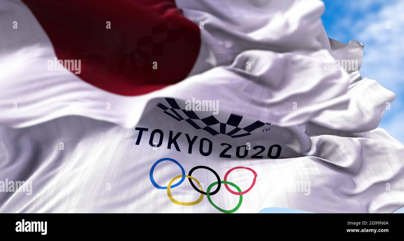 Tokyo, Giappone, 2021 luglio: La bandiera olimpica di Tokyo 2020 sventolava con la bandiera giapponese offuscata in primo piano. Messa a fuoco selettiva. Tokyo 2020 giochi olimpici w Foto Stock