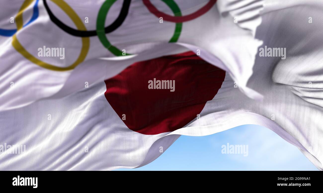 Tokyo, Giappone, luglio 2021: La bandiera nazionale del Giappone sventolava con la bandiera olimpica offuscata in primo piano. Le olimpiadi di Tokyo 2020 sono state rinviate Foto Stock