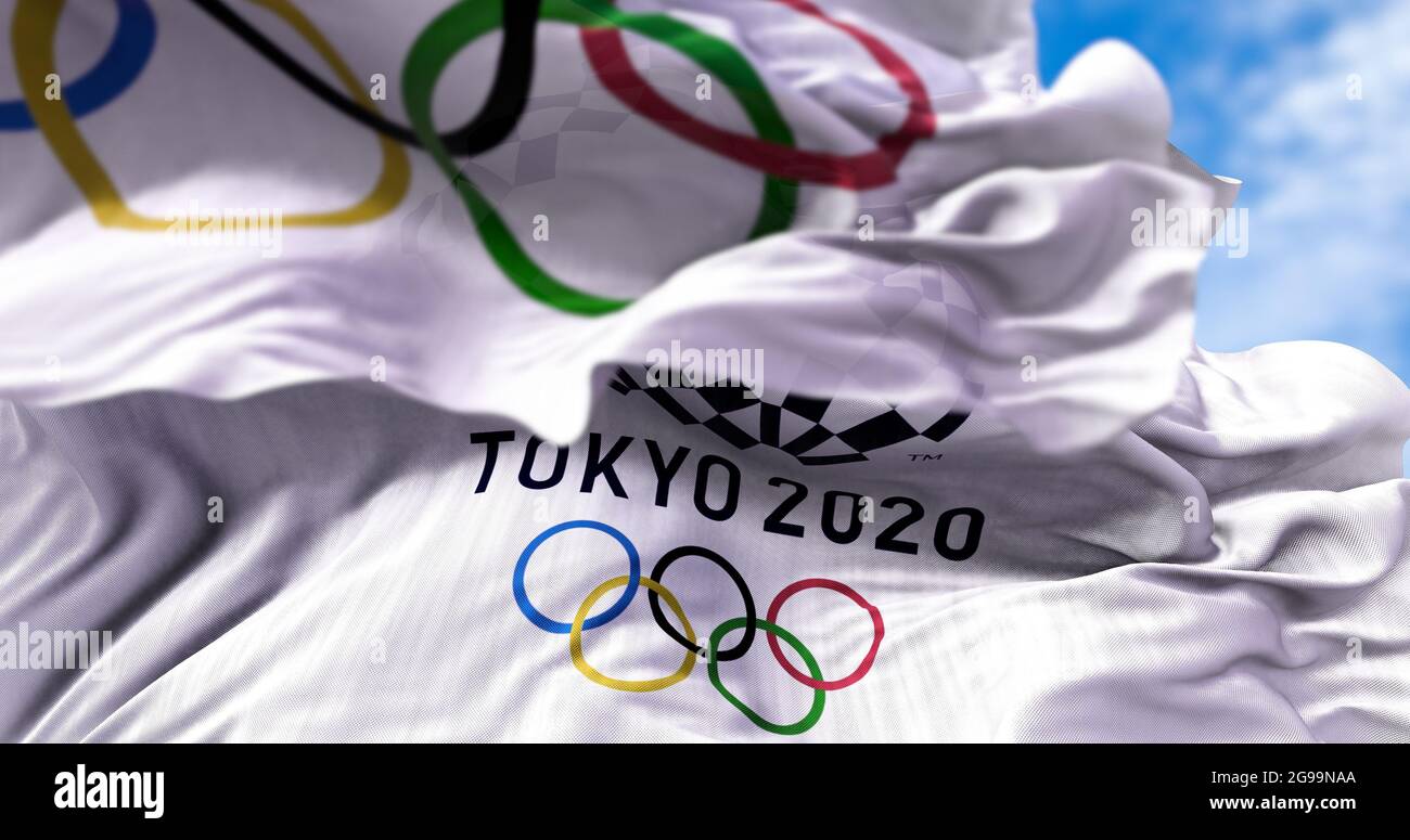 Tokyo, Giappone, 2021 luglio: La bandiera olimpica di Tokyo 2020 sventolava con la bandiera olimpica offuscata in primo piano. Messa a fuoco selettiva. Tokyo 2020 giochi olimpici noi Foto Stock