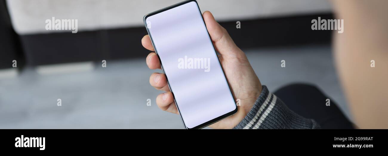 L'uomo tiene lo smartphone con lo schermo bianco in mano Foto Stock