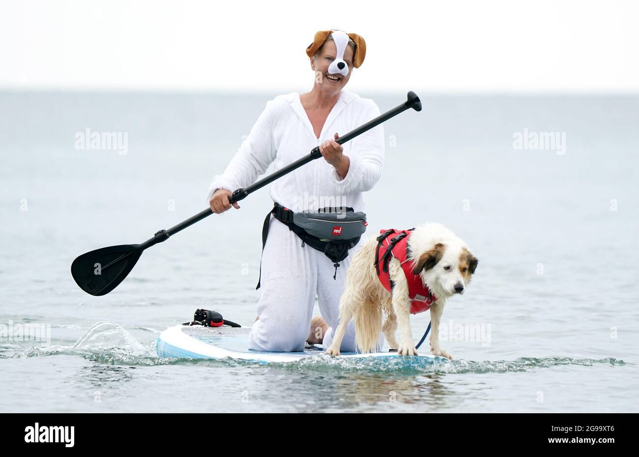 Liz Wilkinson e il suo cane germinale Diogie prendono parte a Dogmasters, l'unico campionato del paese per il surf con i cani e il paddleboard, a Branksome Beach a Poole, Dorset. Data immagine: Domenica 25 luglio 2021. Foto Stock