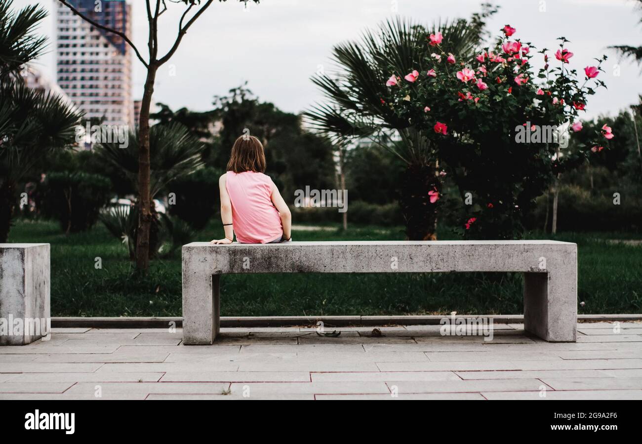 Bambina seduta da sola sulla panchina Foto Stock