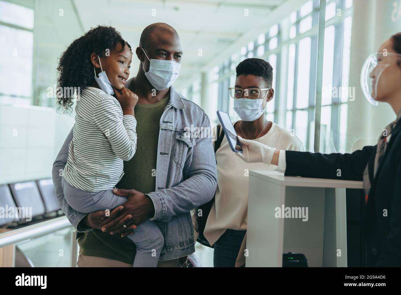 Famiglia turistica al cancello di partenza con compagnie aeree in caso di pandemia. Il personale dell'aeroporto assiste l'uomo africano con la ragazza e la moglie al cancello di partenza. Foto Stock