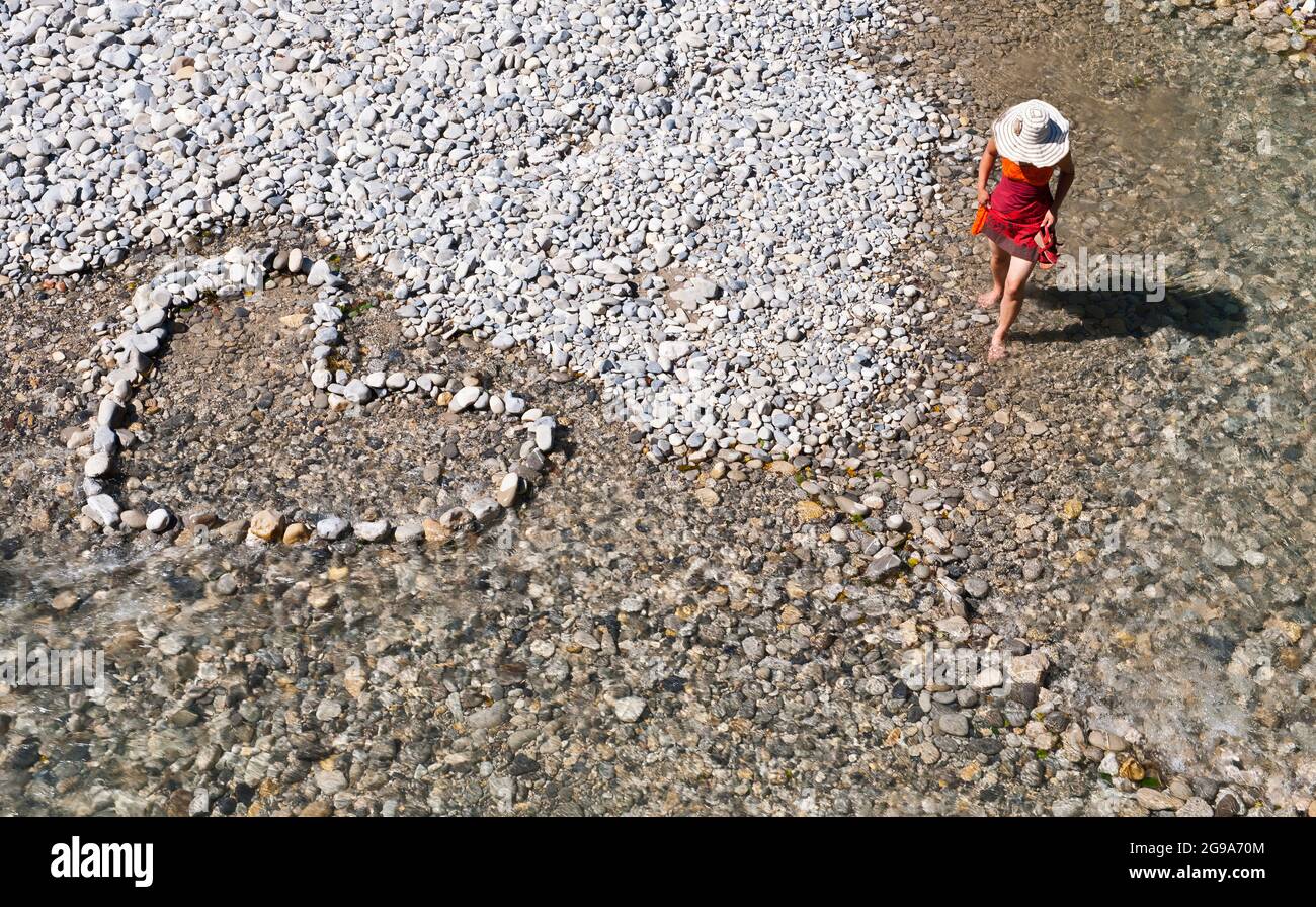 donna che cammina a piedi nudi nel fiume vicino ad un anello di pietra a forma di cuore Foto Stock