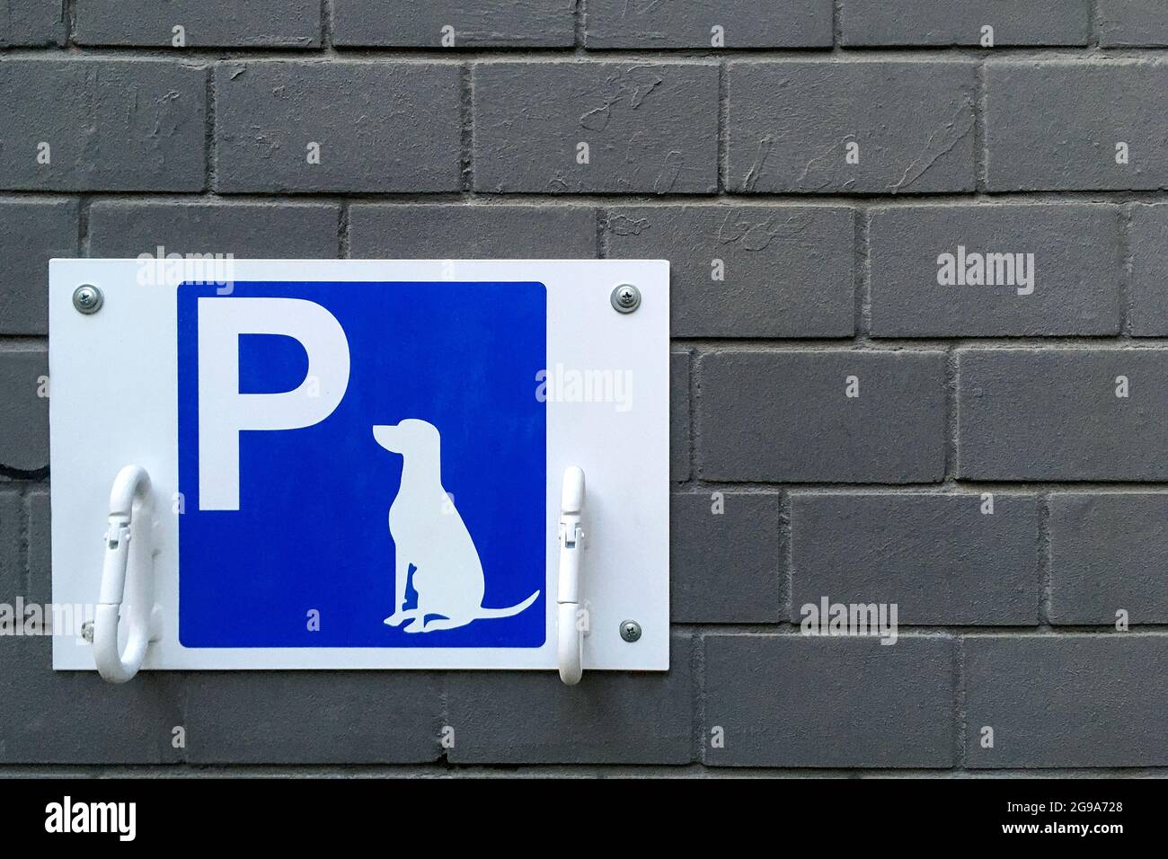 Cartello di parcheggio per cani designato sulla targa blu. Posto per cani da bind in attesa di proprietari all'esterno, con anelli per fissare il guinzaglio, in luogo pubblico o Sho Foto Stock