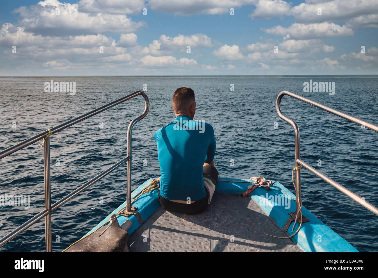 Vista posteriore dell'uomo seduto ad arco di una barca che guarda al mare Foto Stock