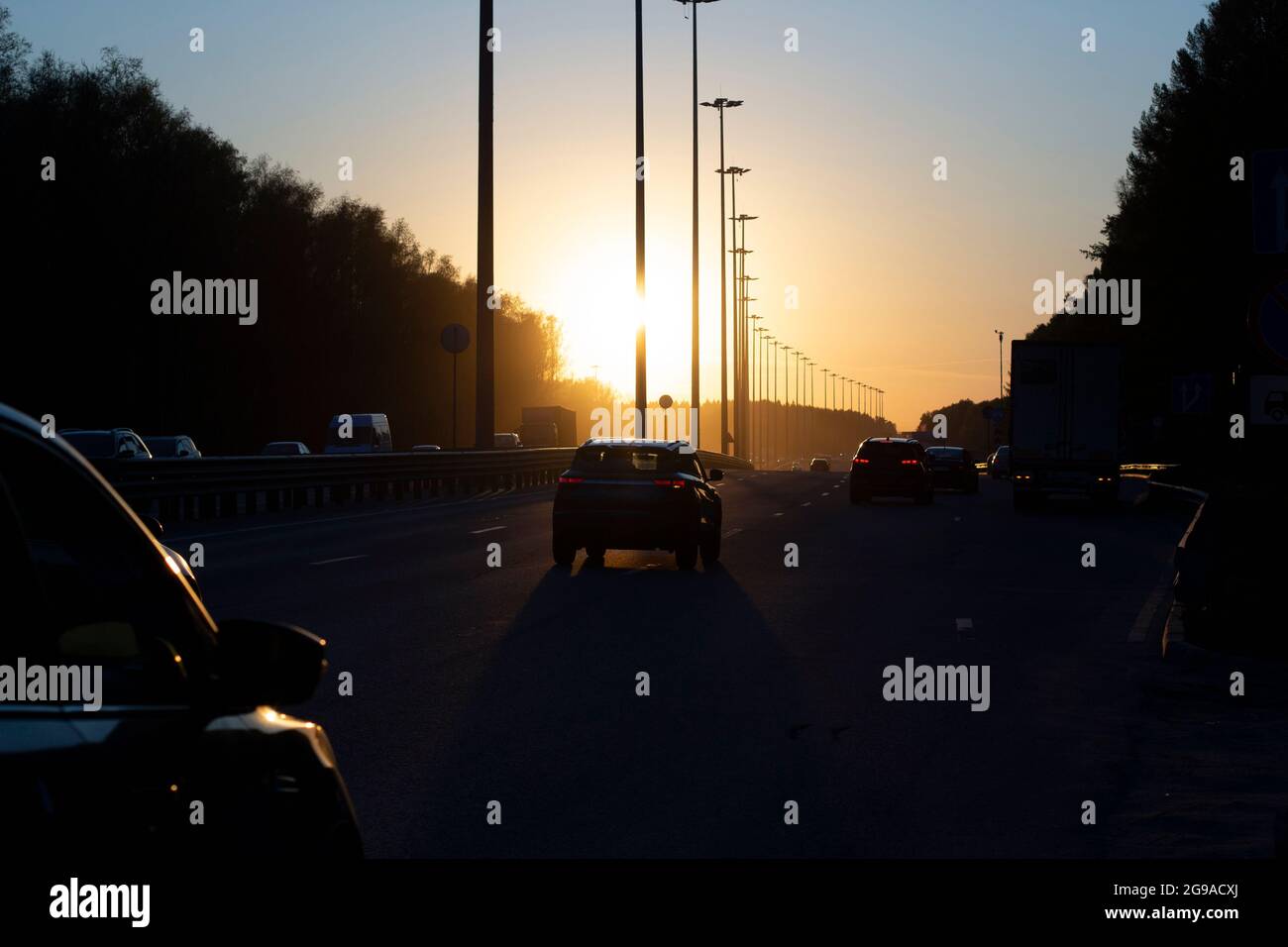 Tramonto sull'autostrada. Il sole tramonta sull'autostrada. Autostrada a carico. Auto in auto dalla città in serata. Foto Stock