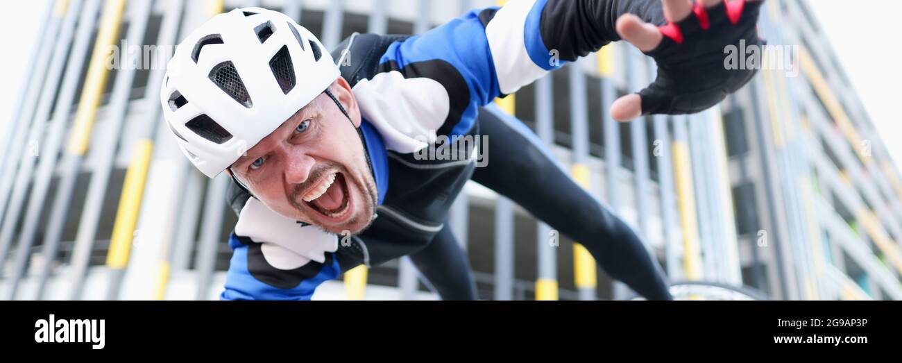 Il giovane ciclista maschio che indossa casco e indumenti protettivi è caduto bici e ritratto volante Foto Stock