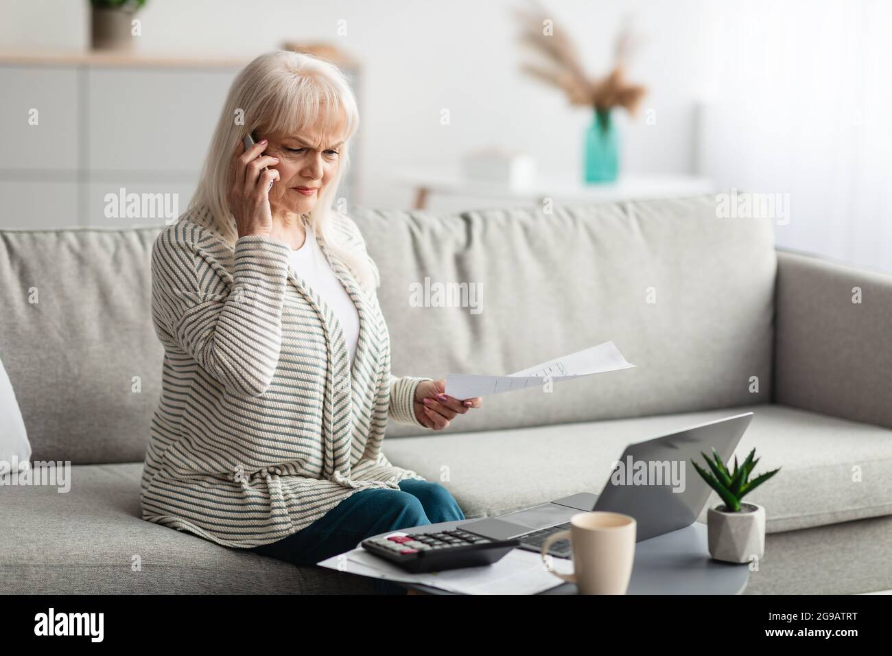 Donna matura che lavora e parla sul cellulare a casa Foto Stock