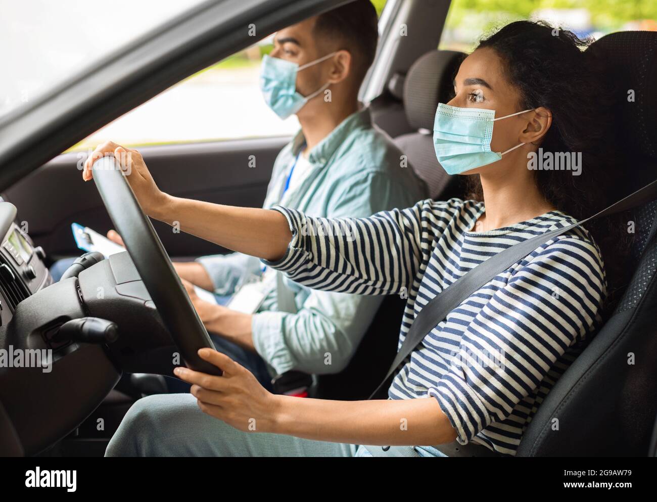 Donna bruna imparare a parcheggiare a scuola guida mentre pandemia Foto Stock