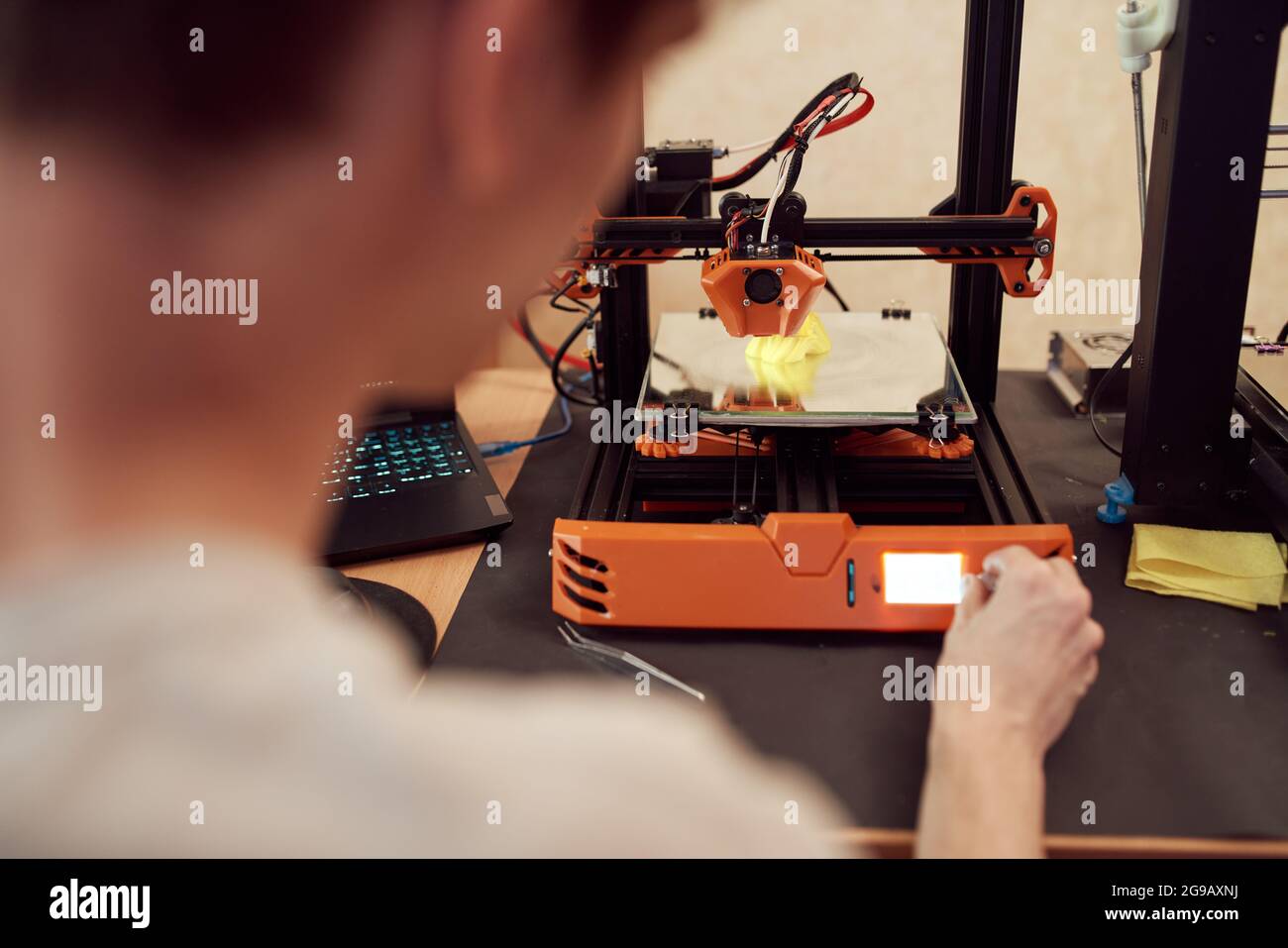 Angolo elevato di controlli di regolazione maschili anonimi sulla stampante 3D durante la creazione di un modello in plastica in officina Foto Stock