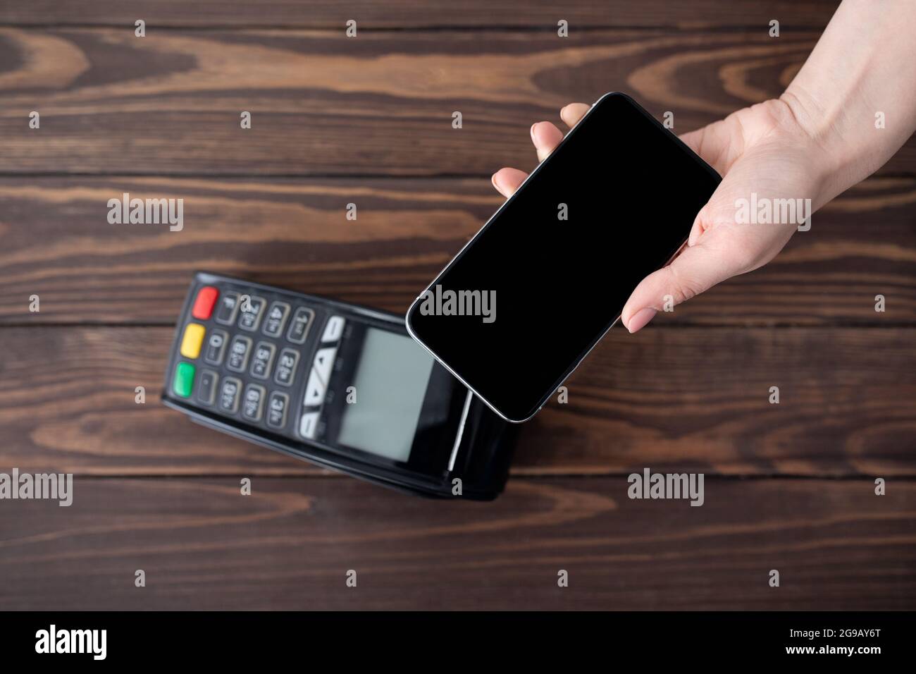 Vista dall'alto del cliente che paga online dallo smartphone utilizzando la moderna tecnologia Easy nfc, tenendo il cellulare con schermo vuoto Foto Stock