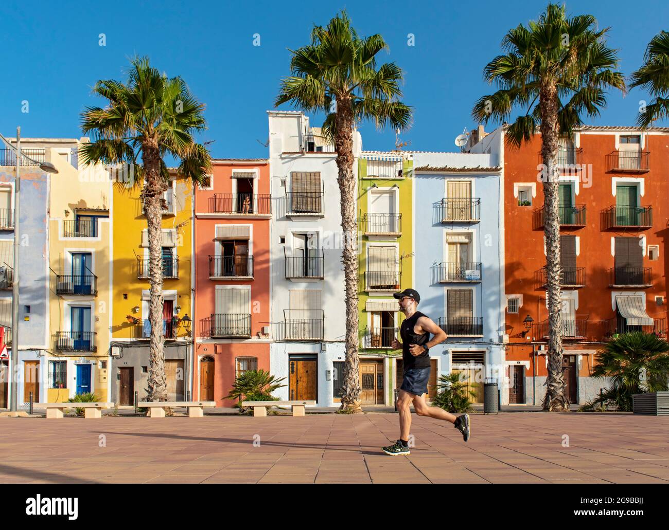 Runner di fronte a colorate case fronte spiaggia, Cases de Colors, Carrer Arsenal, Villajoyosa, Spagna Foto Stock