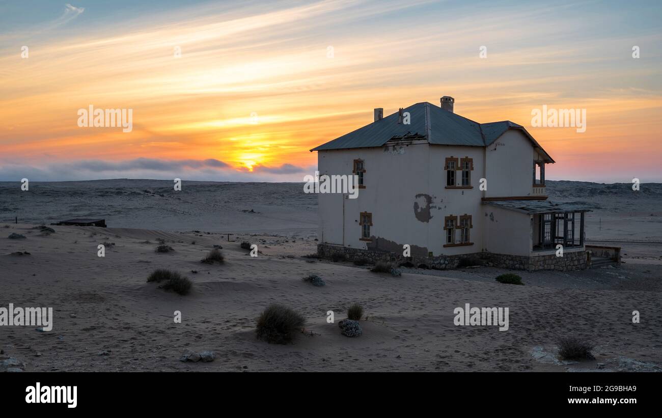 Edificio abbandonato al tramonto nella vecchia città mineraria dei diamanti di Kolmanskop vicino a Luderitz, deserto del Namib, Namibia. Foto Stock