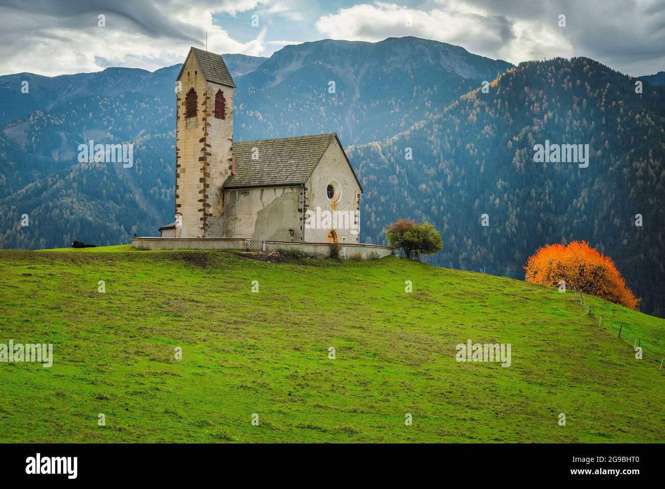 Famosa chiesa di San Giacomo sul prato verde. Antica chiesa e alte montagne sullo sfondo, vicino al villaggio di Santa Maddalena in Funes valle Foto Stock