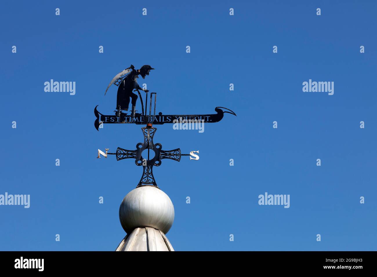 Weathervane con le parole 'Lest Time ti rimbalzerà fuori' sopra un chiosco a Durham City, Inghilterra. La figura raffigura il tempo del Padre con una falce. Foto Stock