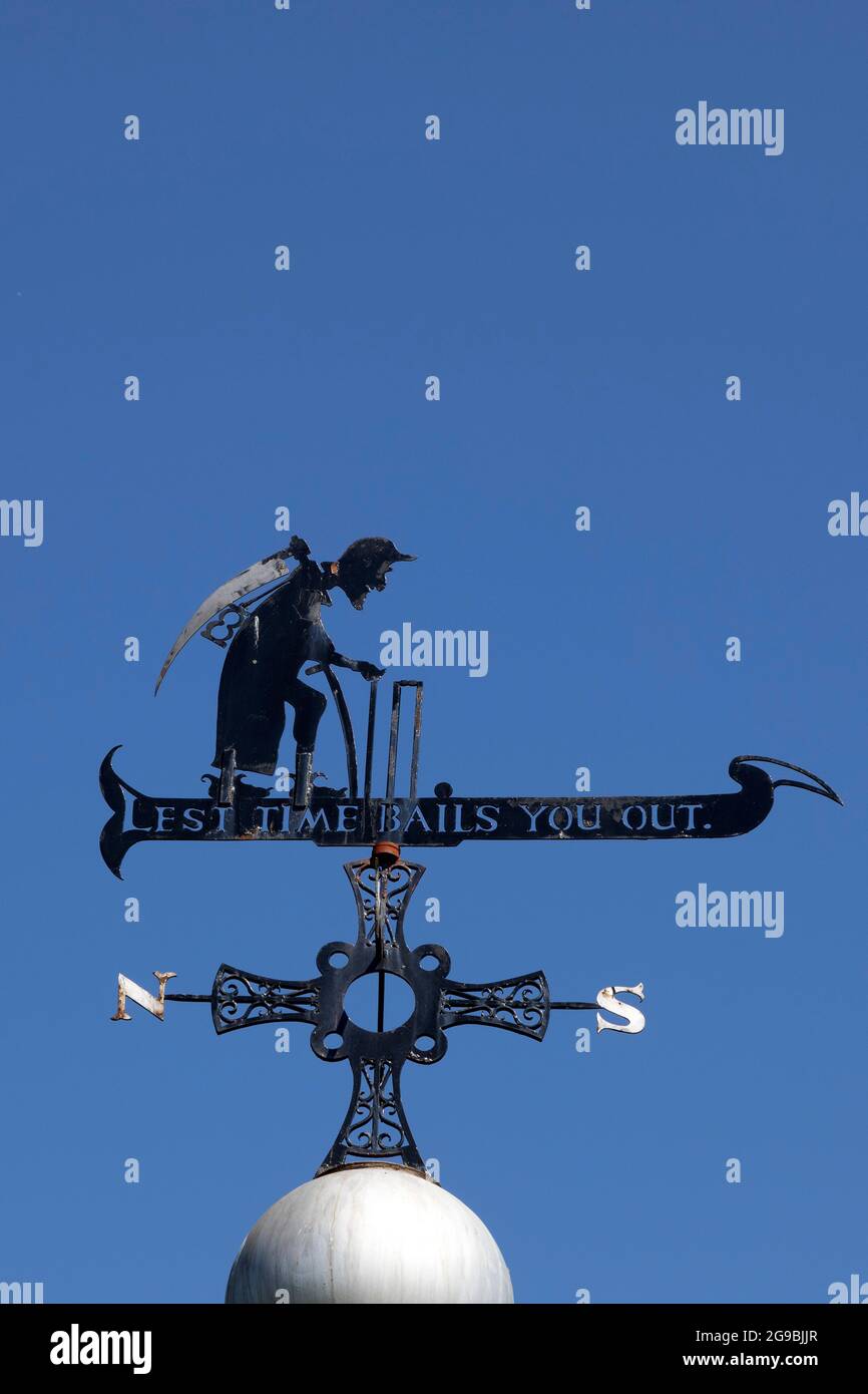 Weathervane con le parole 'Lest Time ti rimbalzerà fuori' sopra un chiosco a Durham City, Inghilterra. La figura raffigura il tempo del Padre con una falce. Foto Stock