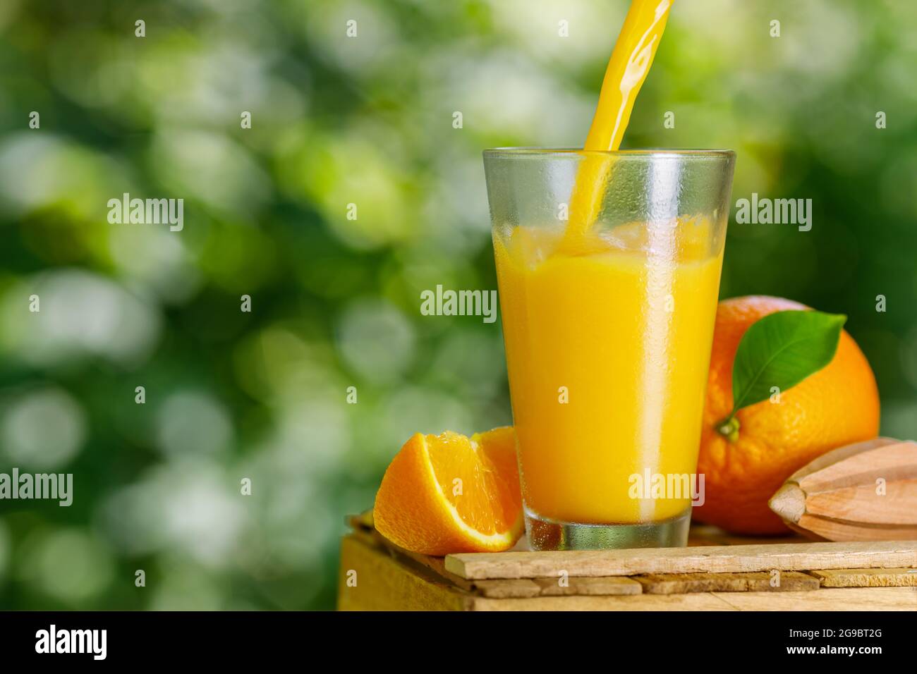 succo d'arancia freddo appena spremuto che viene versato in un bicchiere Foto Stock