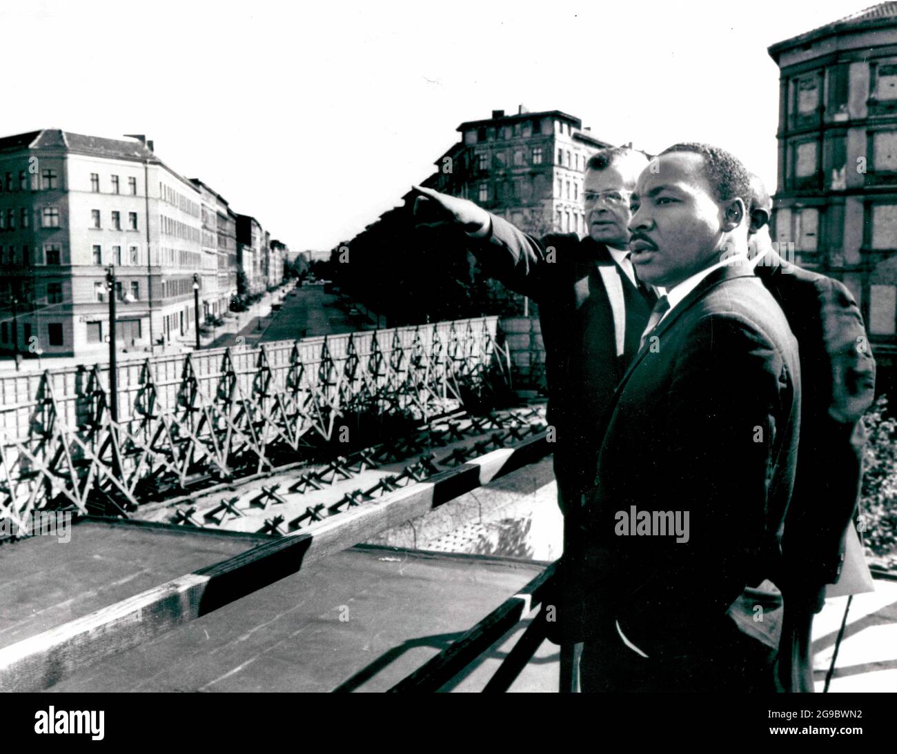 Germania, Berlino -- Dr. Martin Luther King al confine del settore sovietico del Muro in Bernauer Strasse. Herr Werner Steltzer, direttore del Centro informazioni di Berlino, indica i punti di interesse, 1964 Foto Stock