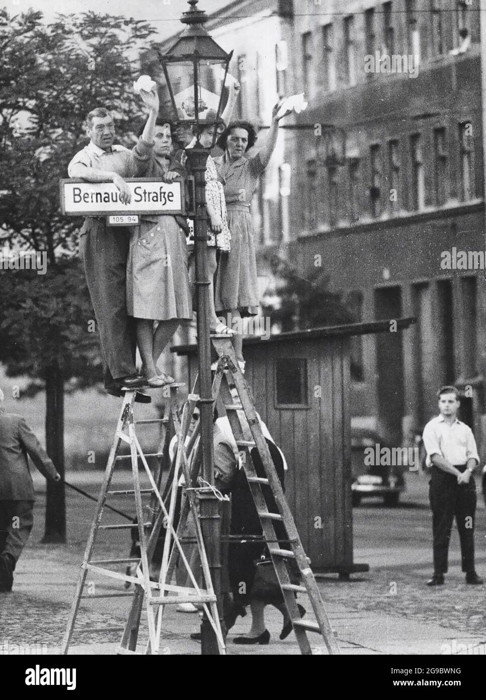 I cittadini di Berlino Ovest si levano in piedi sulle scale per salutare gli amici e i cari sul lato orientale del muro di Berlino, circa 1961 Foto Stock
