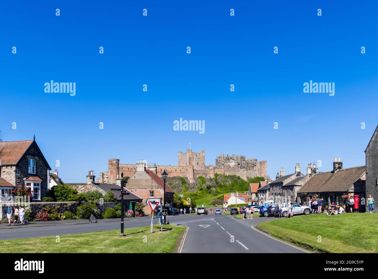 L'iconico Castello di Bamburgh, un edificio storico di grado i sulla costa nord-orientale dell'Inghilterra, visto dal villaggio di Bamburgh, in Northumberland, su un soleggiato dd Foto Stock