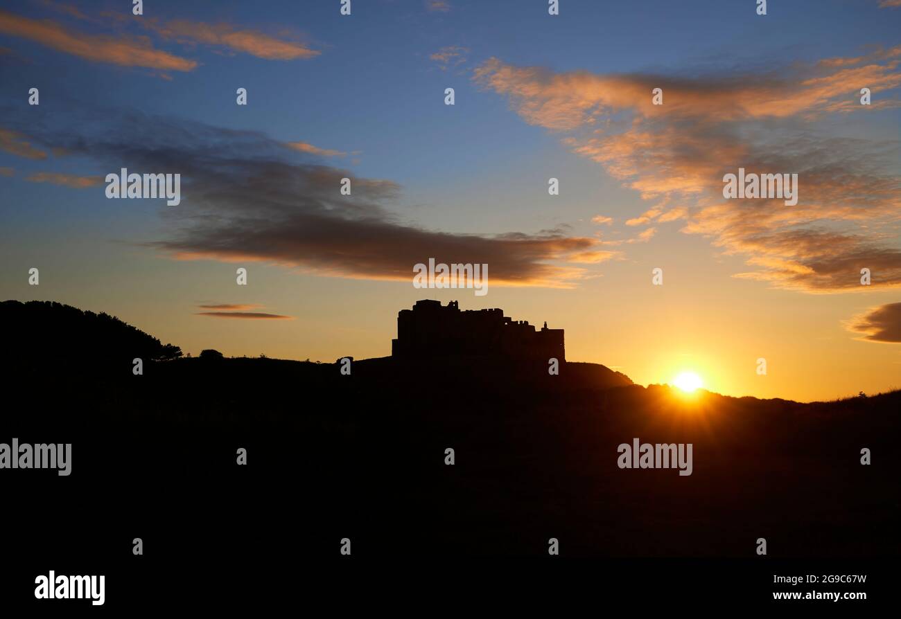 L'iconico Castello di Bamburgh sulla costa nord-orientale dell'Inghilterra, vicino al villaggio di Bamburgh in Northumberland, visto sullo skyline al tramonto all'ora d'oro Foto Stock