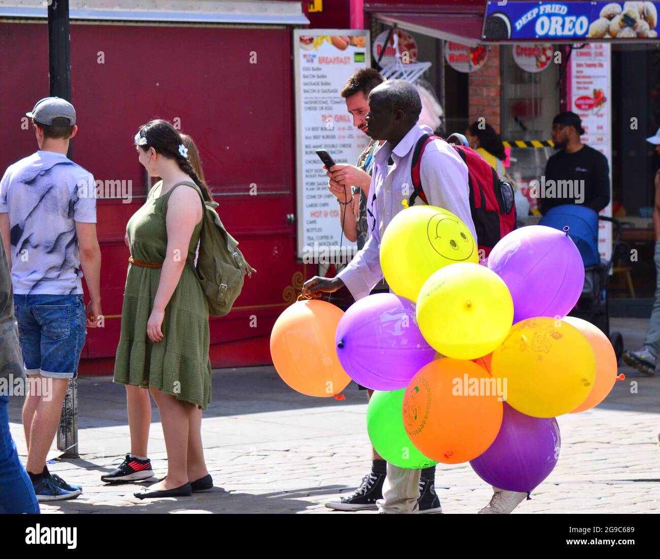 Un uomo che vende palloncini cerca clienti nel centro di Manchester, Inghilterra, Regno Unito. Foto Stock