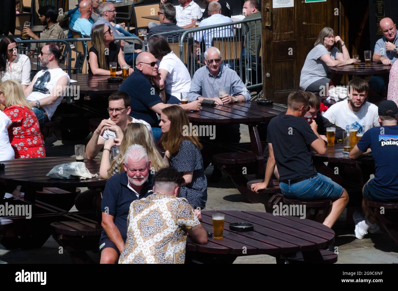 La gente gode del sole estivo mentre si siede all'aperto in un pub nel centro di Manchester, Inghilterra, Regno Unito. Foto Stock
