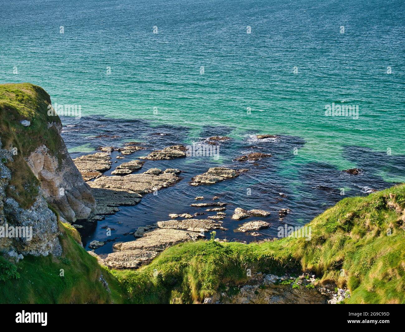 Piattaforma di taglio delle onde - rocce costiere erose dall'azione delle onde - vicino a Portrush sulla costa di Antrim Causeway nell'Irlanda del Nord, Regno Unito. Preso su un sole Foto Stock