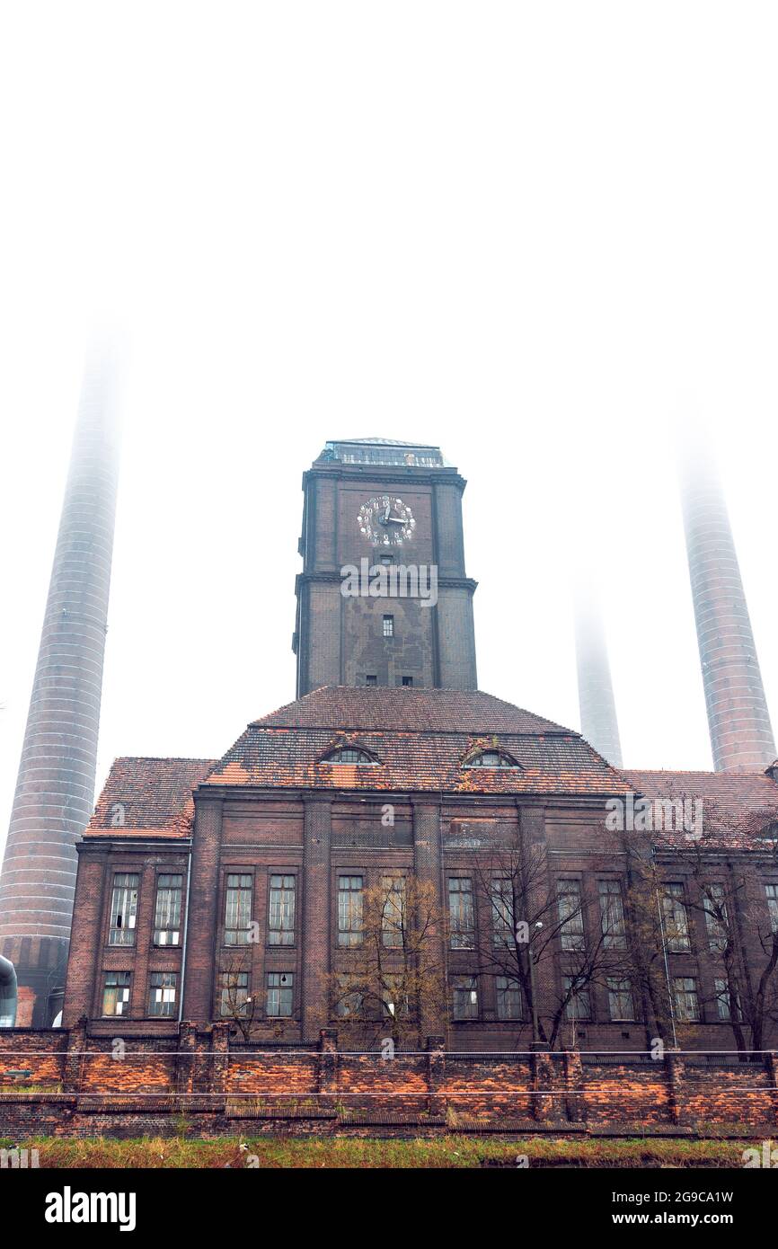 Vecchia centrale a carbone nel distretto di Szombierki a Bytom, Slesia, Polonia. Industriale, edificio in mattoni con torre dell'orologio e camini in un giorno foggy. Foto Stock