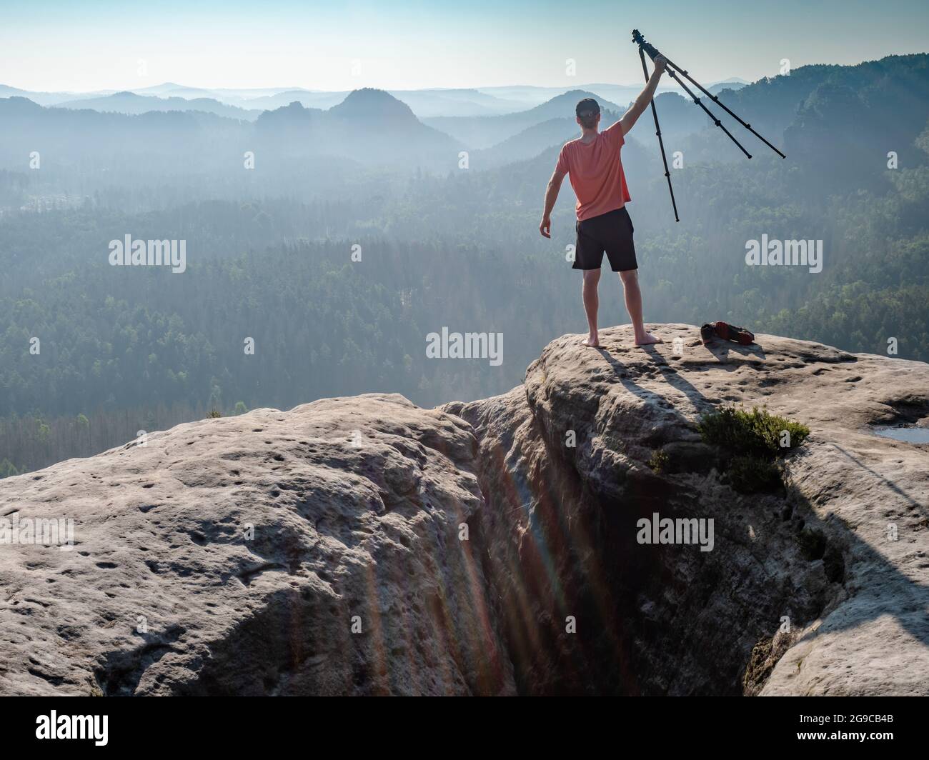 Il fotografo tiene un treppiede con una fotocamera in alto nell'aria e si rallegra in una bella giornata. Amante della natura e fotografo di paesaggio. Foto Stock