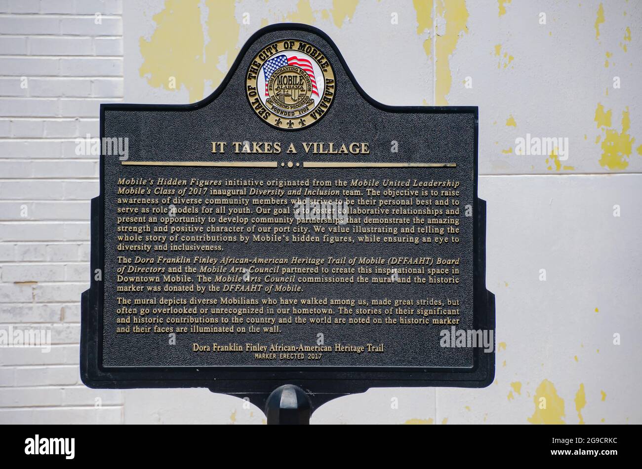Accanto al "IT takes a Village Mural", che raffigura dei più importanti Mobiliani, il 23 luglio 2021, a Mobile, Alabama, si trova un marcatore storico. Foto Stock