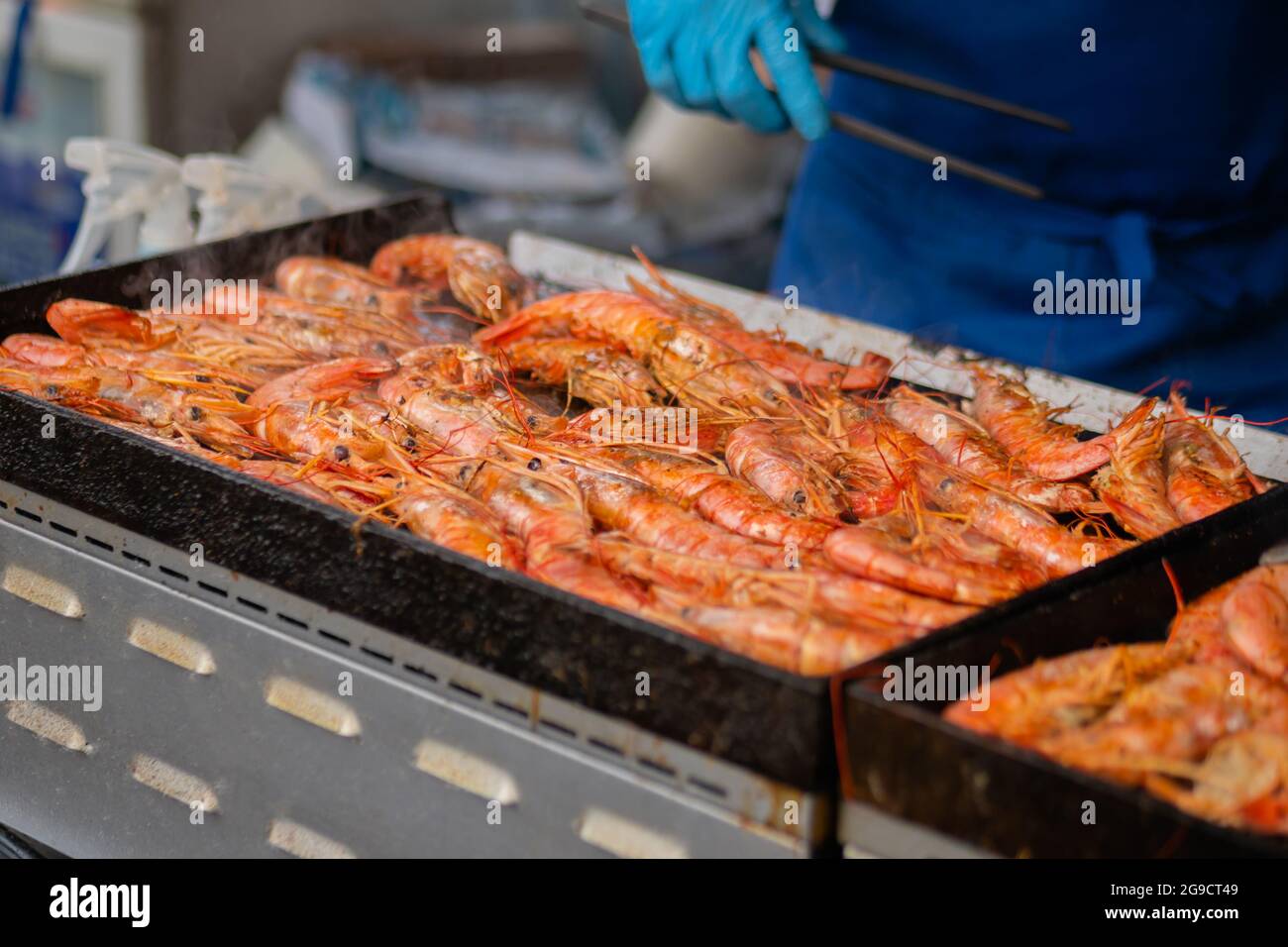 Chef che cucinano gamberi rossi di langoutine freschi, gamberi alla griglia a cibo locale estivo Foto Stock