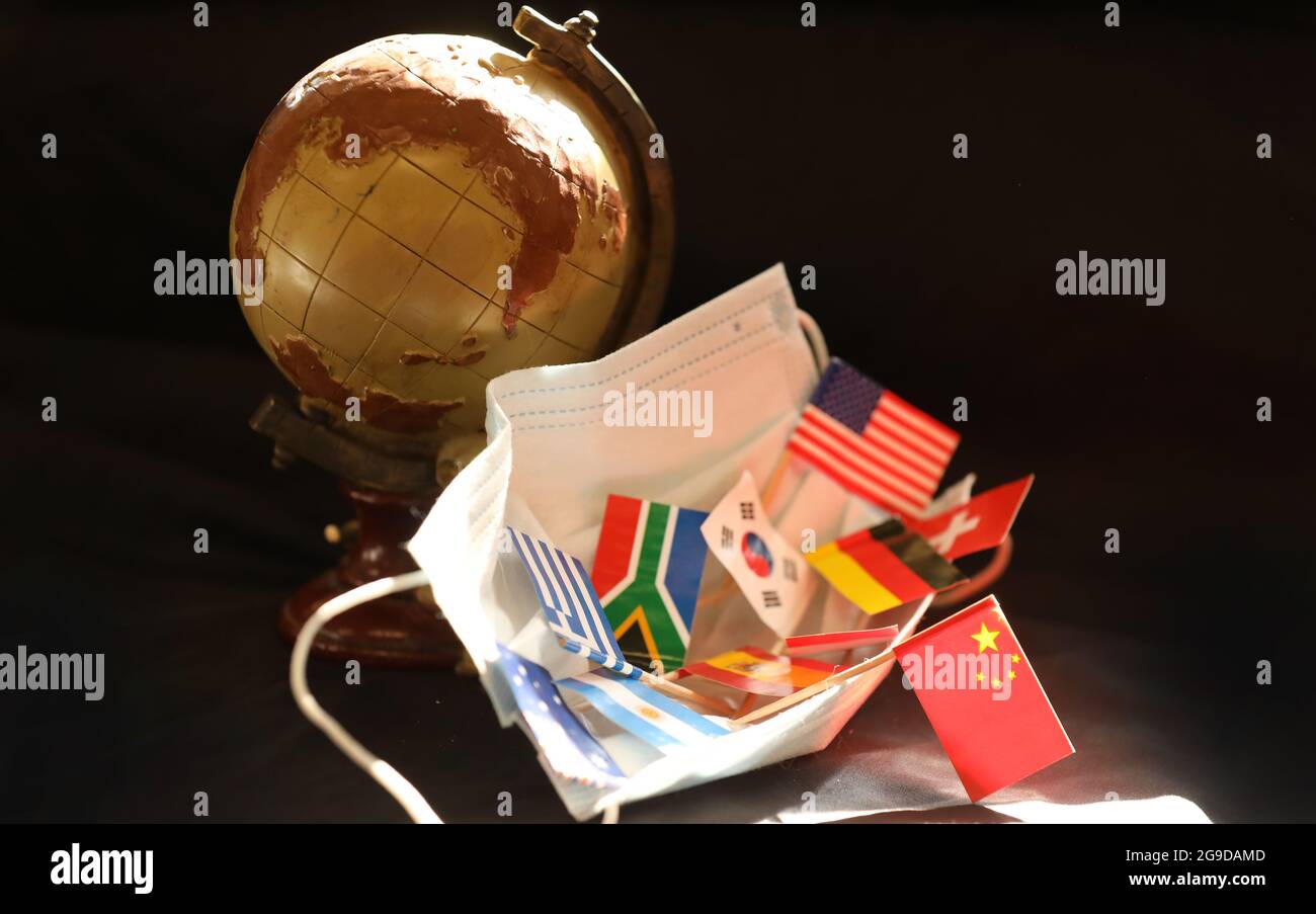 Una collezione di bandiere internazionali all'interno di una maschera di sicurezza covid con il globo di stile olden giorni sullo sfondo. Cina prominente bandiera nazionale cinese Foto Stock