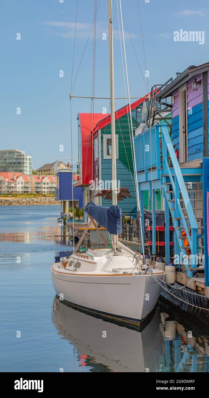 Bella vista mattutina dello yacht ormeggiato su un molo da colorate boathouses nel Fisherman Wharf Village Victoria, BC, Canada. 23 luglio 2021. Via Foto Stock